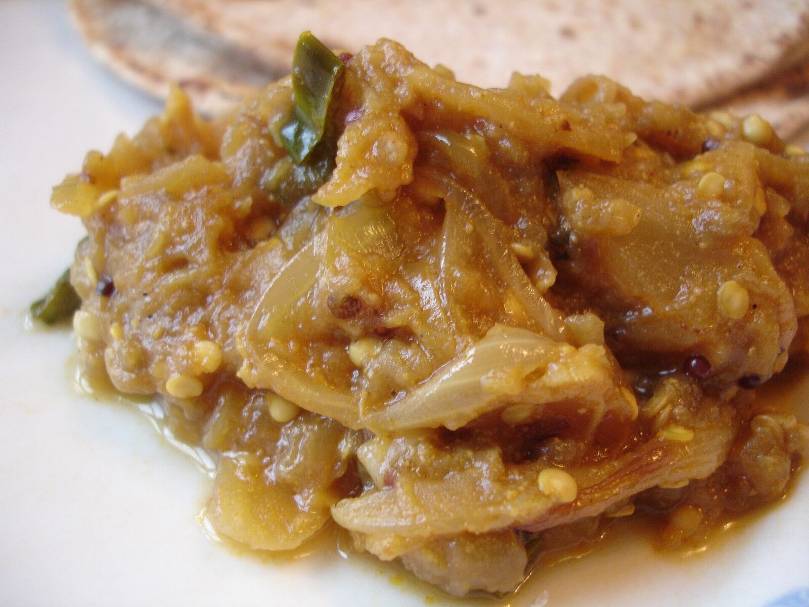 This simple dish is very popular across India. I used the recipe <a href=" http://allrecipes.com/Recipe/Baingan-Bharta-Eggplant-Curry/Detail.aspx " rel="noreferrer nofollow">here</a> With a few variations: Take 3 medium size (long purple) aubergines. Wash and dry with a kitchen towel. Coat them with vegetable oil and make 4-5 lengthwise skin deep cuts on each aubergine. This makes it easy to remove the skin after it is baked. <a href=" https://www.flickr.com/photos/rovingi/753308978/in/photostream/ ">see</a> Place in a pre-heated oven for 40 minutes at 200 deg C until they become soft. When the baked aubergines are cool enough, peel off the skin by hand and remove the stalk. Mash the flesh of the aubergine coarsely with a potato masher or a spoon. <a href=" https://www.flickr.com/photos/rovingi/752454471/in/photostream/ ">see</a> Heat 4 tbsp of oil in a thick bottomed vessel. Flavour the oil with cumin & mustard seeds, 1/2 tsp turmeric powder, a pinch of asafotedia and 3 chopped green chilies. Add one medium sized finely sliced onion and fry on medium heat until translucent. Add finely chopped ginger and garlic and fry for 2 min. Add 1 tsp chili powder, 1 tbsp garam masala (curry powder), 1 tbsp Sambar powder and fry for 2 min. Add 1/2 cup stirred plain yogurt and mix well. Fry & mix until the sauce regains it's colour. Add the mashed baked aubergine & salt and mix. Cook on low heat for 30 min. Serve with chapati. The traditional way of making this dish is by roasting the aubergines over an open flame (of a gas hob) instead of baking it. This gives it a wonderful smoked flavour that is really the signature of this dish. But it's always easier to bake it in an oven.