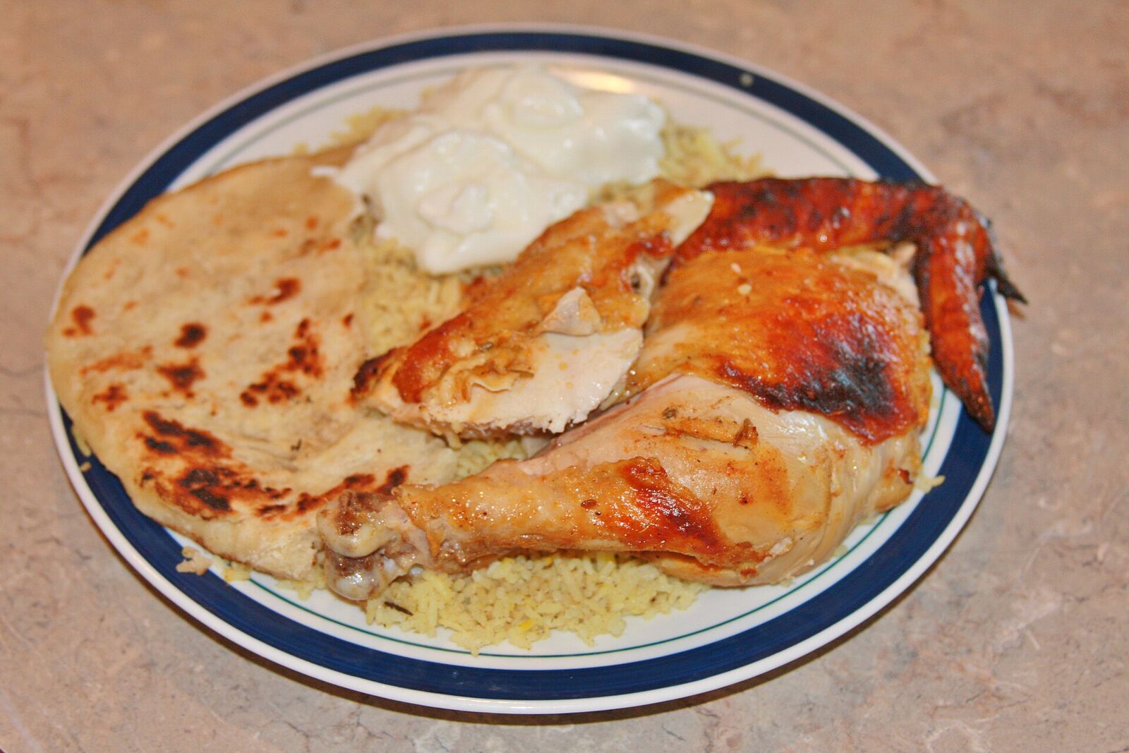 Grilled Tandoori Chicken Makes 4 to 6 servings 2 tablespoons Basic Ginger-Garlic Paste 1 (2.5 - 3 pound) whole chicken, skinned. 2 tablespoons fresh lime or lemon juice 1/2 teaspoon salt, or to taste 1/3 cup nonfat plain yogurt, whisked until smooth 2 tablespoons heavy cream 1 tablespoon peanut oil 1 teaspoon garam masala 1 teaspoon ground dried feungreek leaves 1/2 teaspoon ground cumin 1 teaspoon ground paprika 1/4 teaspoon cayenne pepper, or to taste 1/8 teaspoon ground turmeric 1 tablespoon melted butter for basting Cooking: 1. Leave the chicken whole, with a sharp knife make deep, 1.5 inch cuts all over the chicken -- 3 on each breast, 3 on each thigh, and 2 on each drumstick. Then place in a non-reactive dish. In a small bowl, mix together the lime juice and salt and rub it over the chicken, making sure to reach inside the cuts. Cover with plastic wrap and marinate in the refrigerator about 2 hours. Meanwhile, prepare the ginger-garlic paste. 2. After the chickne has marinated, in another small bowl, mix together the yogurt, cream, oil, ginger-garlic paste, garam masala, fenugreek leaves, and cumin. 3. Heat the oil in a small nonstick saucepan over medium-high heat until hot but not smoking. Remove from the heat and add teh paprika, cayenne pepper, and turmeric. Mix the spiced oil into the yogurt mixture. Rub the yogurt well over the inside the chicken. Cover with plastic wrap and marinate in the refrigerator, at least 8 and up to 24 hours. 4. To grill: Preheat the grill to medium-high (about 375 - 400 degrees F). Grill, turning the chicken as needed, until the meat is soft and charred in a few places and opaque inside, 20 - 25 minutes. Baste with the melted butter and grill, turning, another 3 to 5 minutes. 5. To Bake: Adjust oven rack to lowest position and heat oven to 325 degrees. Place vertical roaster on rimmed baking sheet. Slide chicken onto vertical roaster so chicken stands upright and breast is perpendicular to bottom of pan. Roast until skin just begins to turn golden and instant-read thermometer inserted into thickest part of breast registers 140 degrees, 45 to 55 minutes. Carefully remove chicken and pan from oven and increase oven temperature to 500 degrees. When oven is heated to 500 degrees, place 1 cup water in bottom of pan and return pan to oven. Roast until entire skin is browned and crisp and instant-read thermometer registers 160 degrees inserted in thickest part of breast and 175 degrees in thickest part of thigh, about 20 minutes (replenish water as necessary to keep pan from smoking), rotating bird 180 degrees halfway through cooking. Carefully remove chicken from oven and let rest, still on vertical roaster, 20 minutes. Using kitchen towel, carefully lift chicken off vertical roaster and onto platter or cutting board.